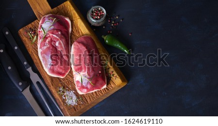 Raw fresh meat, duck breast fillet on wood chopping board. View from above, top view. Copy space for text