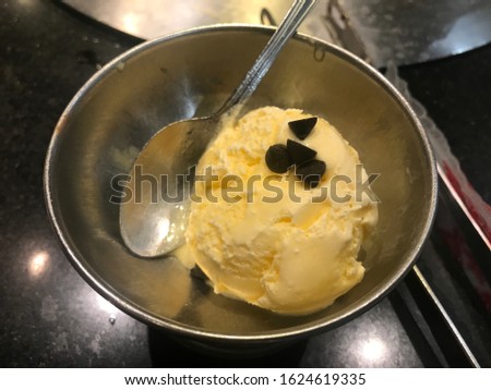 Vanilla ice cream scoop on top with chocolate chips in stainless steel cup