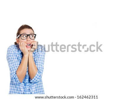 Closeup portrait of young nerdy unhappy woman with black glasses biting her nails and looking upwards with a craving for something or anxious, worried, isolated on white background with copy space.