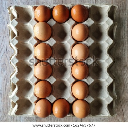 Close-up view of raw brown chicken eggs in egg box on wooden background with "A to Z" collection  as "O" alphabet