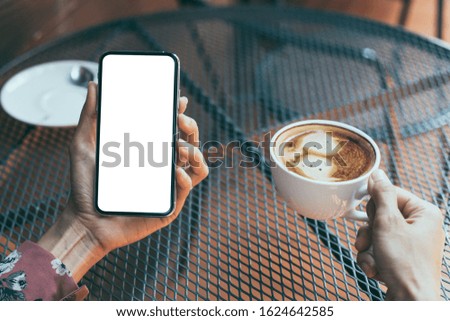 Mockup image blank white screen cell phone.woman hand holding texting using mobile on desk at coffee shop.background empty space for advertise text.people contact marketing business,technology 