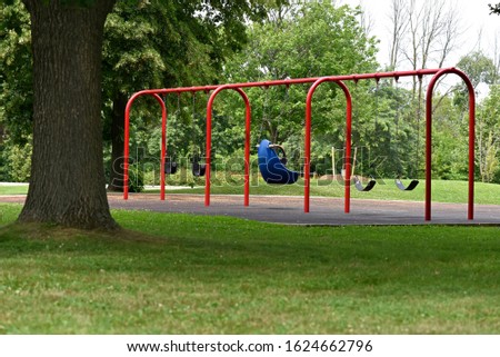 Empty chain swings and one Blue Infant Swing with High Back at the playground in the park in the summer.