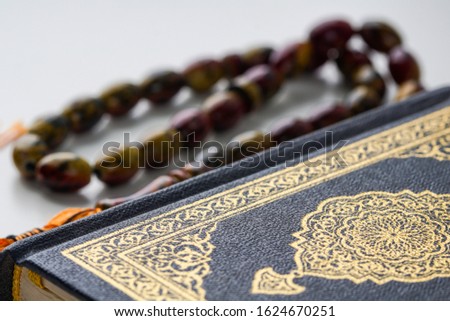 Holy Al Quran with written arabic calligraphy and wooden beads or tasbih on white background.  Selective focus and crop fragment.