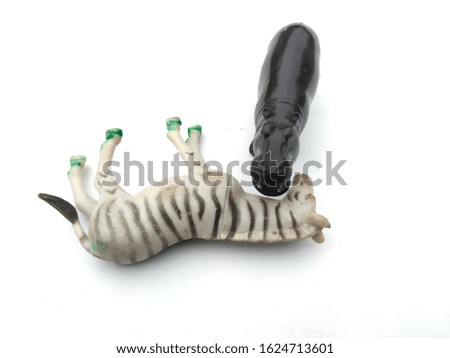 a plastic hippopotamas eating a white zebra isolated on white background
