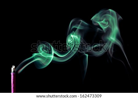 The picture of a smoking incense, isolated on black background. Green smoke. 