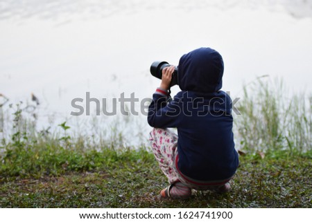 Boy hold digital camera take photo at tke lake