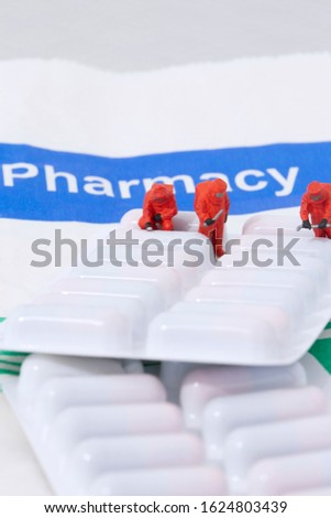 Miniature scale model chemical team with prescription antibiotics medicine in a blister pack on a Pharmacy paper bag.  Checker plate background