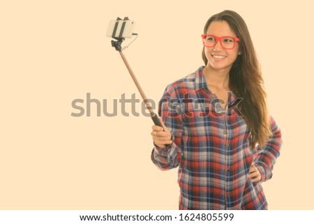 Young happy woman taking selfie with phone on selfie stick