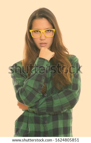 Studio shot of young beautiful woman thinking while wearing eyeglasses