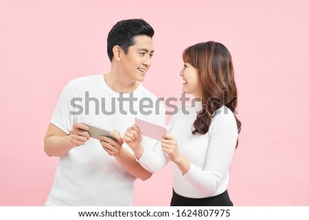technology and people concept - happy couple in white t-shirts with smartphones over pink background