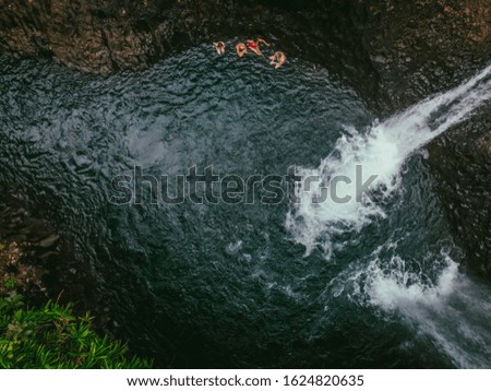 Aerial view of people having a dip in the water beneath 2 gorgeous waterfalls in Fiji