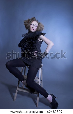Fashion. Young lady in black and with artistic hairstyle.
