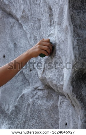 A close-up of the hand of a child climbing a mobile climbing wall
