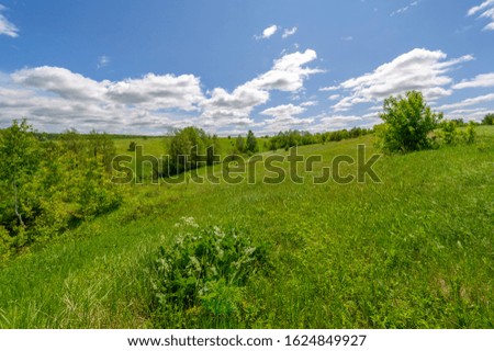 Spring photography, meadows, fields, ravines, hills, rural landscape. A deep, narrow gorge with steep slopes. A naturally raised area of â€‹â€‹land, not as high or craggy as a mountain.
