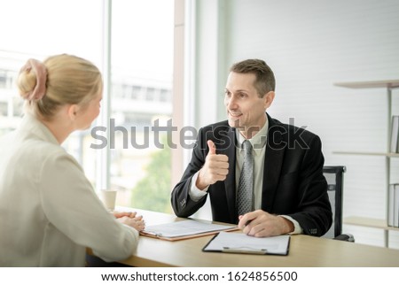 Boss Businessman doing thumbs up congratulation to woman employee at desk in office room