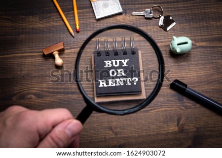 Buy or Rent. Real Estate, Banking, Finance and Tax Concept. Man's hand, holding magnifying glass