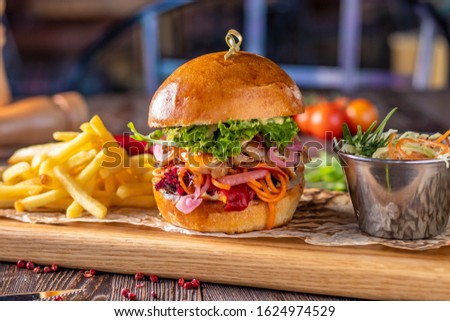 Vegetarian fresh burger with mushrooms and vegetables, served with french fries on a wooden board, healthy fast food