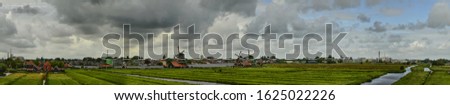 Zaanse Schans, Holland, August 2019. North-east of Amsterdam is a small community located on the Zaan River with several windmills. Panoramic view in large format photography. Day with gloomy clouds.