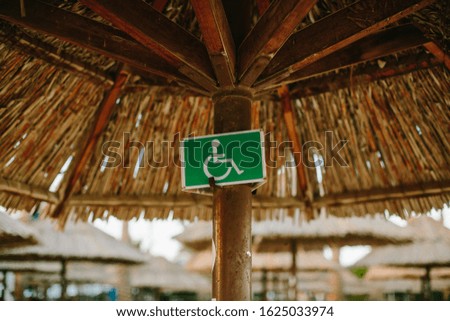 The sign for disabled on the beach near sun bed and umbrellas 