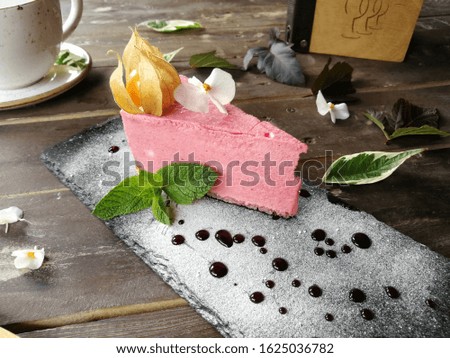 Strawberry mousse on a plate sprinkled with icing sugar, garnished with physalis, flower and mint leaves with chocolate sauce. Photo for the menu of cafes and restaurants