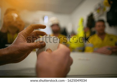 Industrial construction worker holding cards while playing relaxing cards game with his friends during the lunch break  