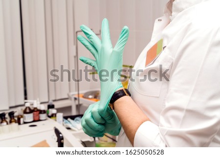 Medical procedures in the office of the ENT specialist. Otorhinolaryngologist doctor pediatrician therapist. Doctor putting rubber gloves on hands. Family reception at a private clinic
