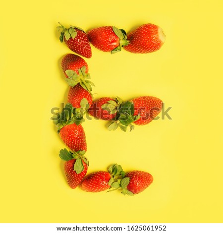 Letter E made from Strawberries on a yellow background. Fruit alphabet.