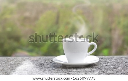 a selective focus picture of a cup of coffee on granite  table in green garden