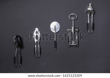 metal kitchen tools lying on diagonal on black colored paper background.