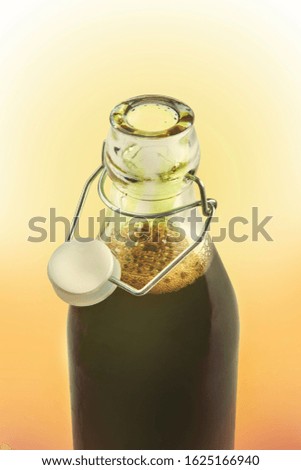 bottle with pumpkin oil detail on orange background  with focus on oil bubbles and cap