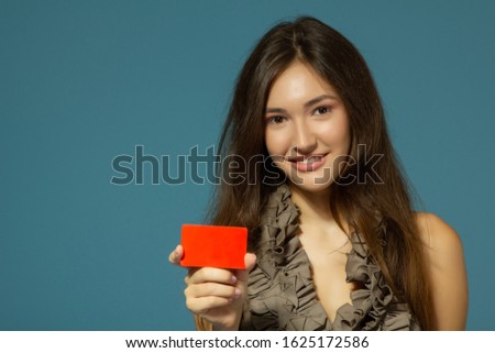 beautiful friendly smiling confident girl showing red card in hand, over blue background