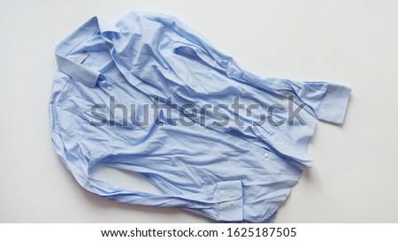 Blue cotton wrinkled and rumpled shirt on white. Washed shirt after tumble dryer Royalty-Free Stock Photo #1625187505