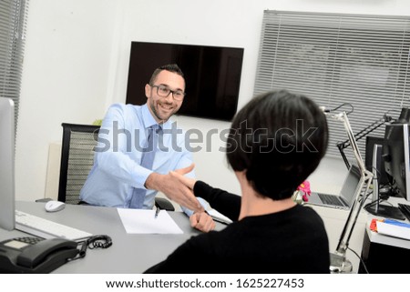 handsome business man with a female client signing contract agreement and shaking hands in office