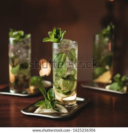 Three lemon mojitos with fresh mint on a wood table with bokeh background