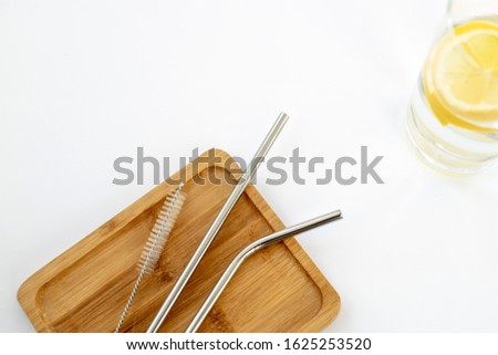 Reusable Metal Straws with Portable Case - Stainless Steel, Eco-Friendly Drinking Straw Set with  Cleaning Brushes. Stainless steel metal straw on a wooden stand. On a white background yellow lemons.  Royalty-Free Stock Photo #1625253520