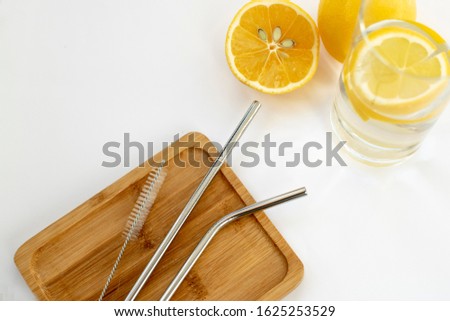Reusable Metal Straws with Portable Case - Stainless Steel, Eco-Friendly Drinking Straw Set with  Cleaning Brushes. Stainless steel metal straw on a wooden stand. On a white background yellow lemons.  Royalty-Free Stock Photo #1625253529