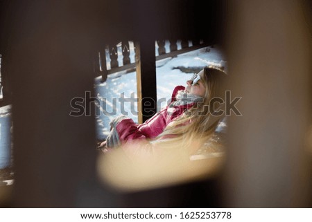 Young woman enjoying sitting in the chair outside on a sunny winter day