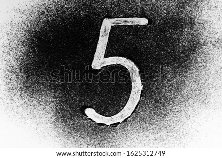 Arabic numerals on a black background with white powder