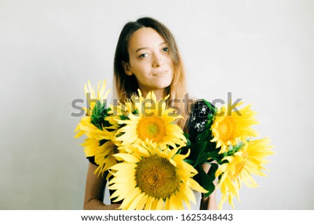 young cute girl holding a yellow vase with sunflower flowers on a white background