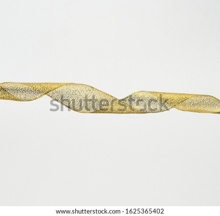 twisted golden silk decorative ribbon for packing gifts on a white background, close up