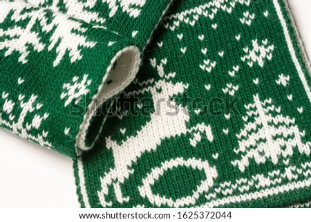 Close-up of piece of green scarf with a white image of a deer, christmas tree and snowflakes