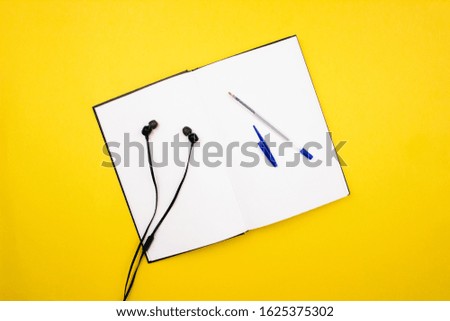 School and office supplies flat lay on colorful yellow background. Notebook, sketchbook, pen, pencil and headphones top view with copy space. Back to school concept. Web template, mockup. Stock photo.