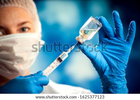 A doctor in medical gloves holding a bottle with vaccine and syringe before doing injection. Close up shot. Medicine and healthcare concept
