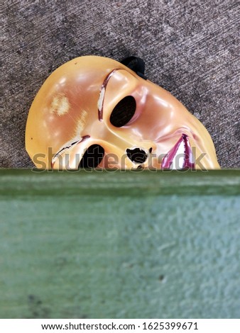 old plastic clown mask discarded under park bench