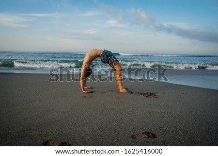 Sportsman practicing Yoga on the sea beach. Benefits of natural environments for physical activity.