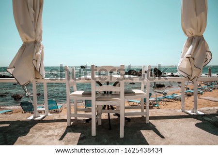 White wooden table with chairs and blurred background of summer beach.Free space for your decoration and landscape of Greece 