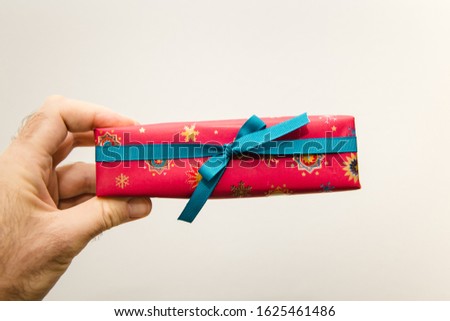 Man hand holding against white background beautifully packaged thin red gift present for the upcoming birthday valentine new year christmas Hanukkah black friday holiday