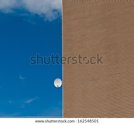 satellite antenna on the house wall against the blue sky on a sunny day