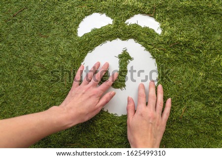Alarm clock made of pine needles. Hands draw. Icon isolated on a green background. Ecology concept.