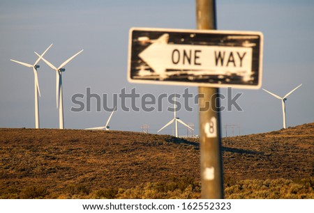 Windmill Farm on a Mountain with One Way Signs Pointing to a Freeway at Dusk